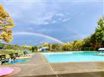 A view of the city pool with a double rainbow