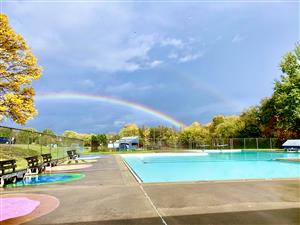 A view of the city pool with a double rainbow
