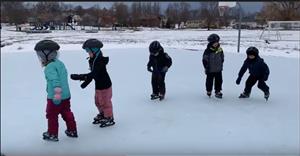 A group of small children ice skating.